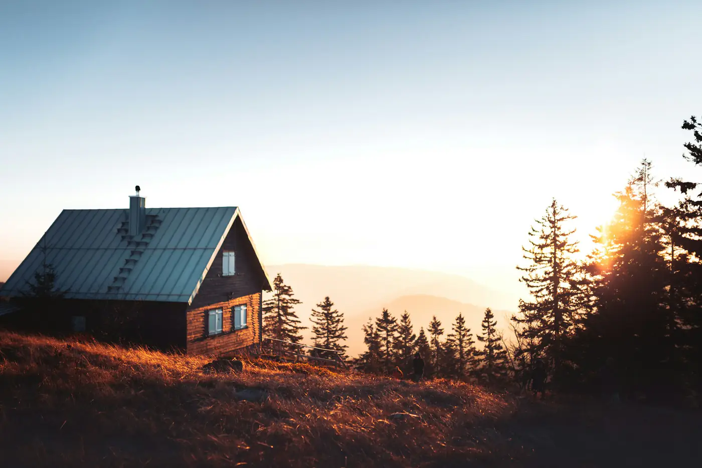 A small wooden house among pine trees at sunrise